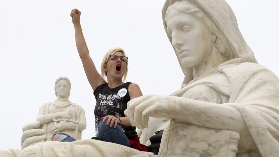 Demonstrator Jessica Campbell-Swanson of Denver, Colorado, sits on the lap of the "Contemplation of Justice" statue outside the US Supreme Court in Washington DC, October 6, 2018