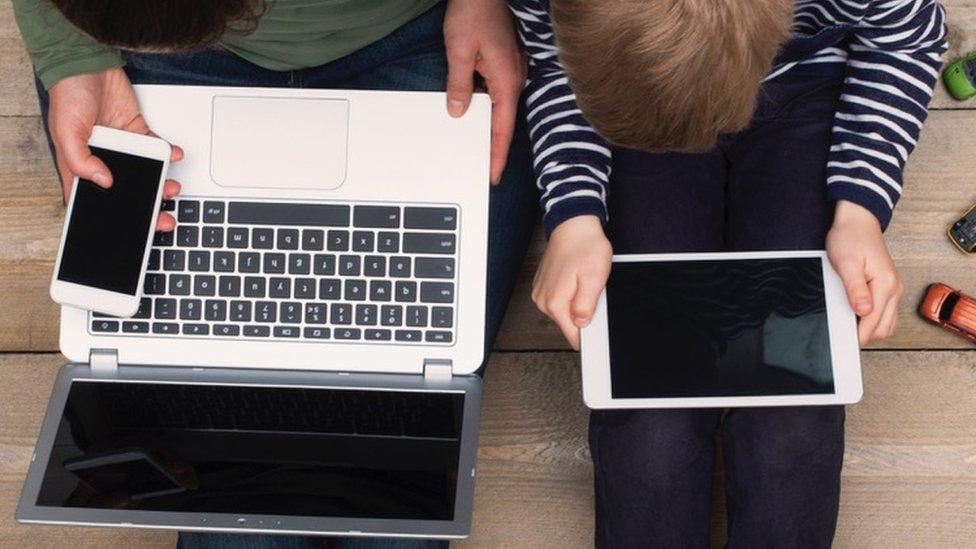 Woman and child with devices on laps