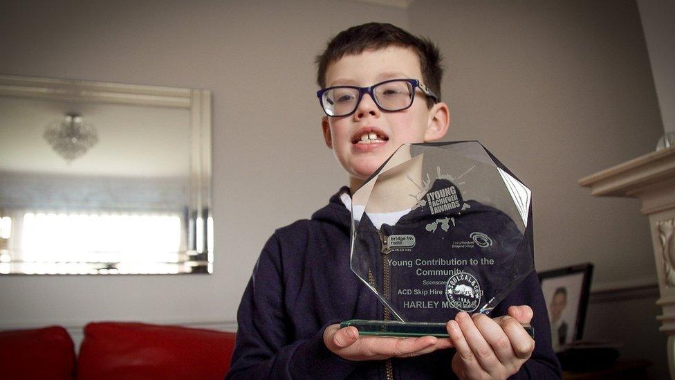 Harley holding a trophy he was given for the work he does to support his mother