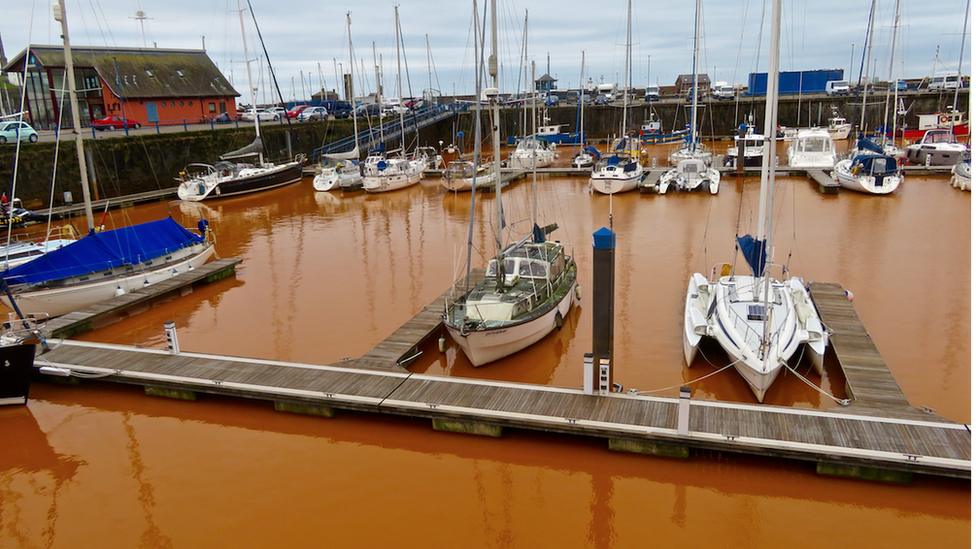 Boats in orange water at Whitehaven Harbour