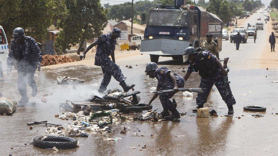 Uganda police officers remove barricades set by people demonstrating on a road in Kasangati on July 9, 2015, after presidential hopefuls former Prime Minister Amama Mbabazi and opposition leader Kizza Besigye were arrested by the Ugandan police.