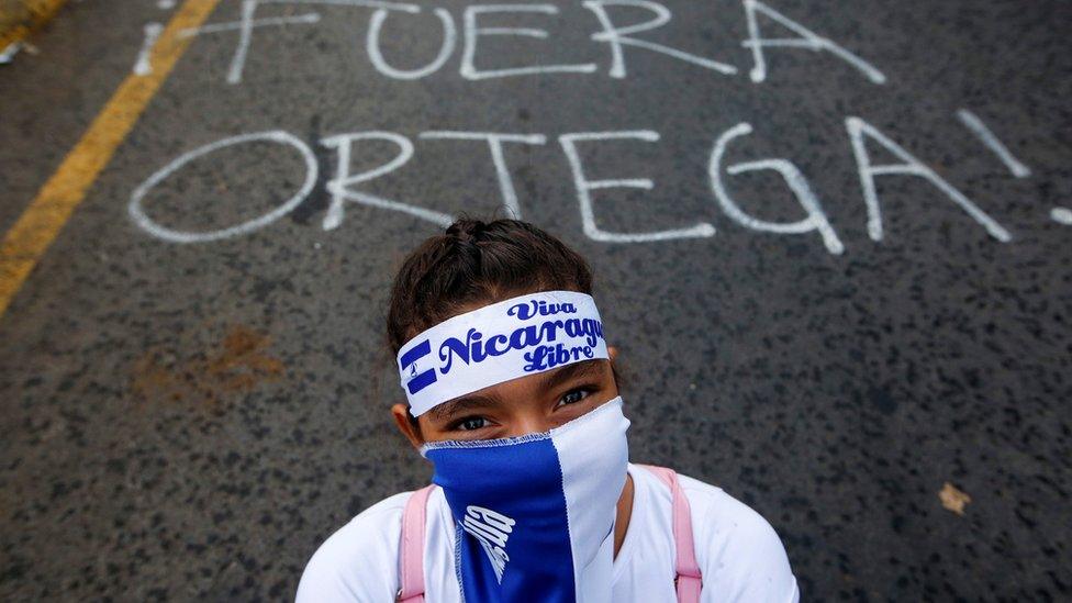 A demonstrator stands next to a graffiti that reads "Ortega Out" during a protest march against Nicaraguan President Daniel Ortega's government in Managua, Nicaragua May 26, 2018