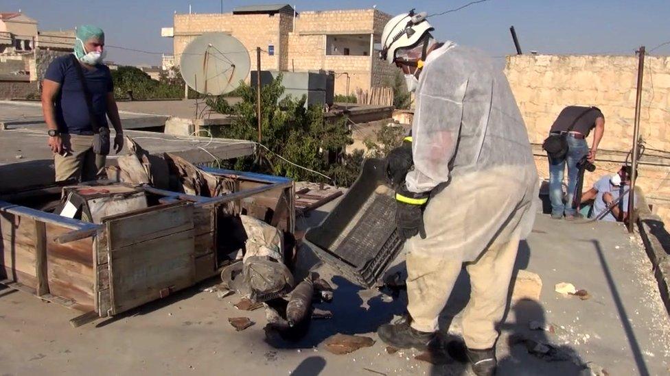 Workers collect samples from the site of an alleged chemical weapons attack in Syria