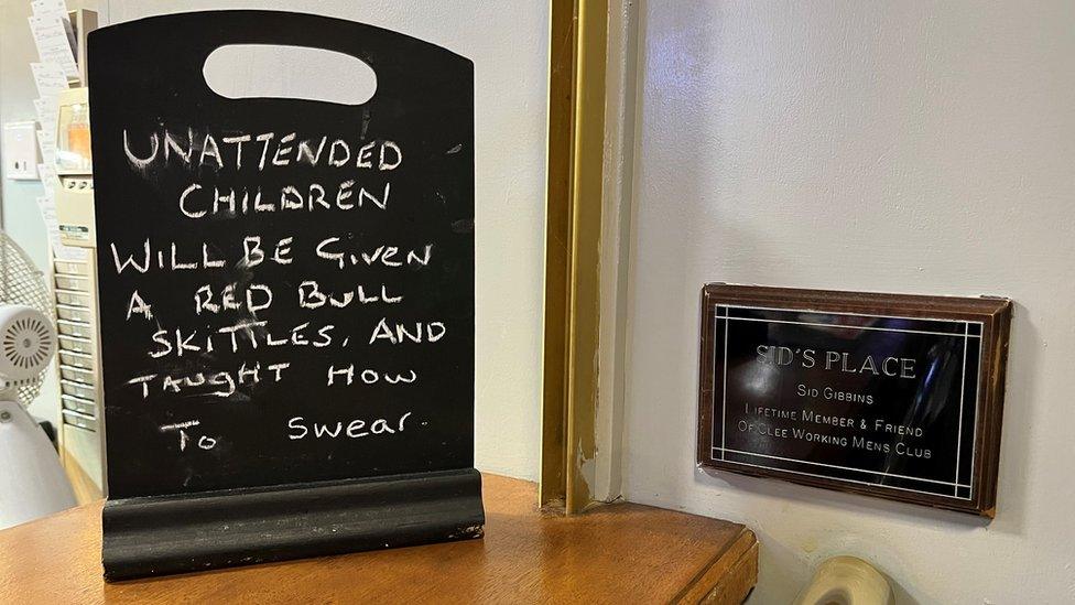 A humorous sign on the bar warning unattended children will be "given a Red Bull and Skittles and taught how to swear"