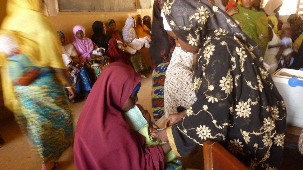 A health worker (R) vaccinates a child at a public health centre where children are being vaccinated against polio in Kano, northern Nigerian, on February 13, 2013.