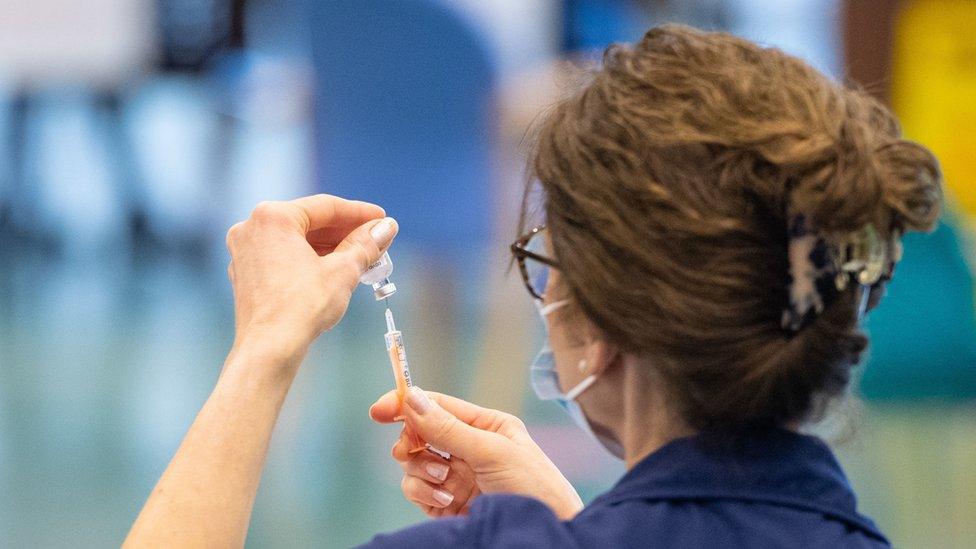 A nurse tests an injection