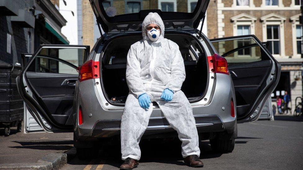 Uber driver Yasar Gorur wears personal protective equipment while cleaning his vehicle