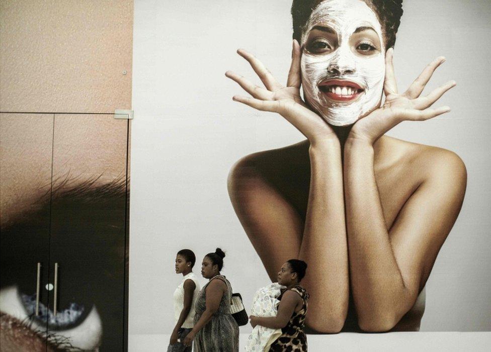 People walk past a clothing retailer shop during the official opening of the "Mall of Africa" in Midrand, South Africa, on April 28, 2016.