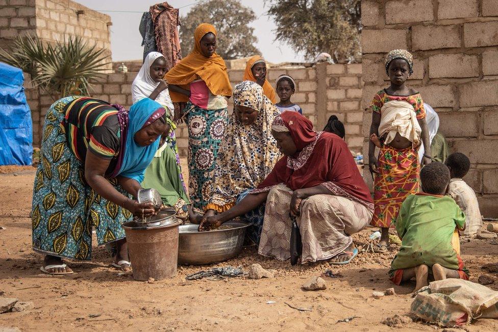 Women and children stand outside accommodation made available by the community for Internally Displaced People (IDP) from northern Burkina Faso in Kaya, on 22 January 2019.