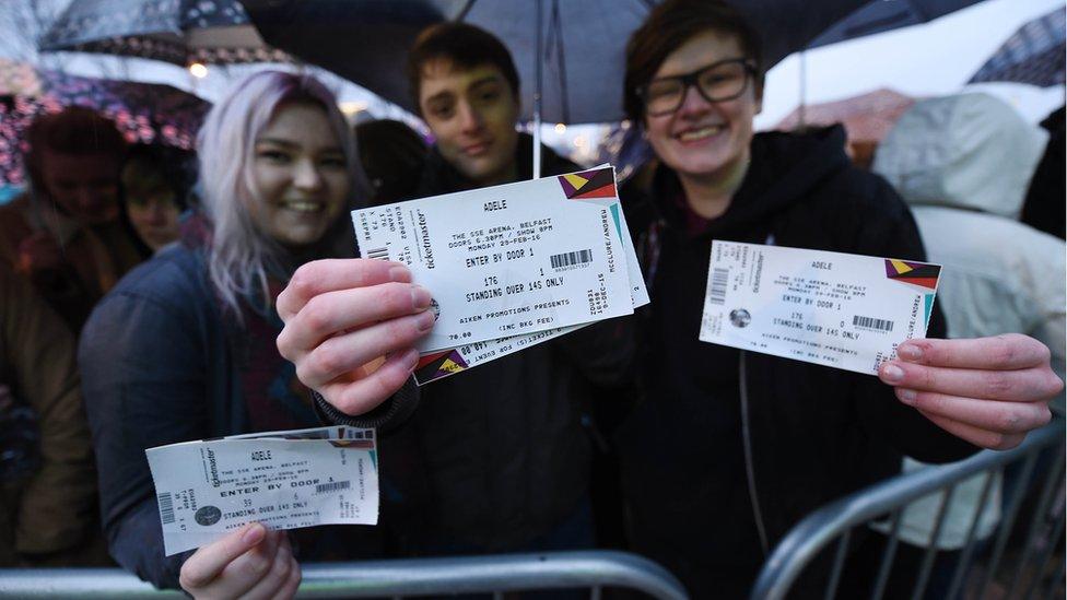 Adele fans at the front of the queue display their tickets as they wait outside the SSE Arena in Belfast