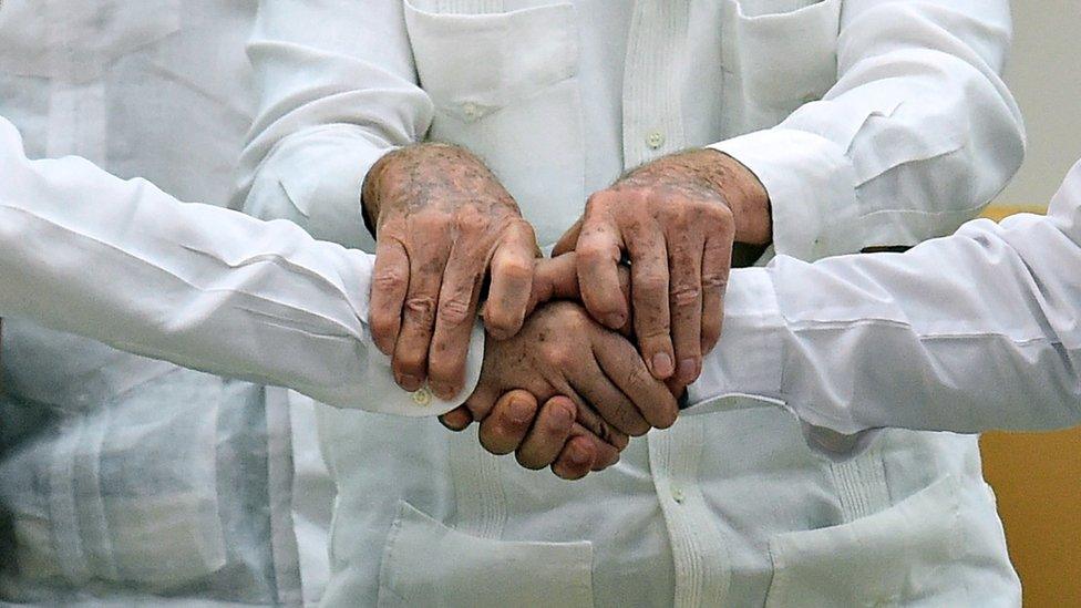 A close-up of the hands of Juan Manuel Santos (left), Raul Castro (centre) and Timochenko (right)