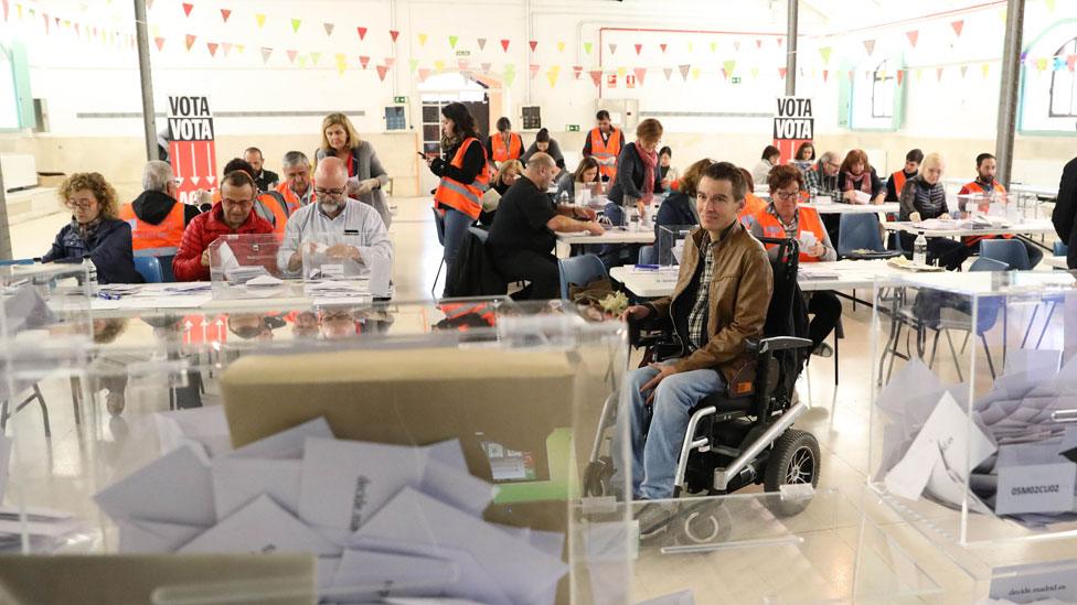 Mr Soto is seen sitting in his wheelchair in the middle of a busy polling station, with ballot boxes stacked neatly filled with papers in the foreground. He appears to be casting his vote