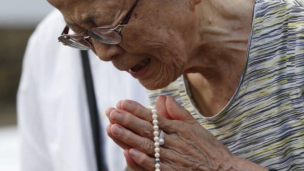 A woman prays for victims of the 1945 atomic bombing in front of the Peace Statue, 9 August