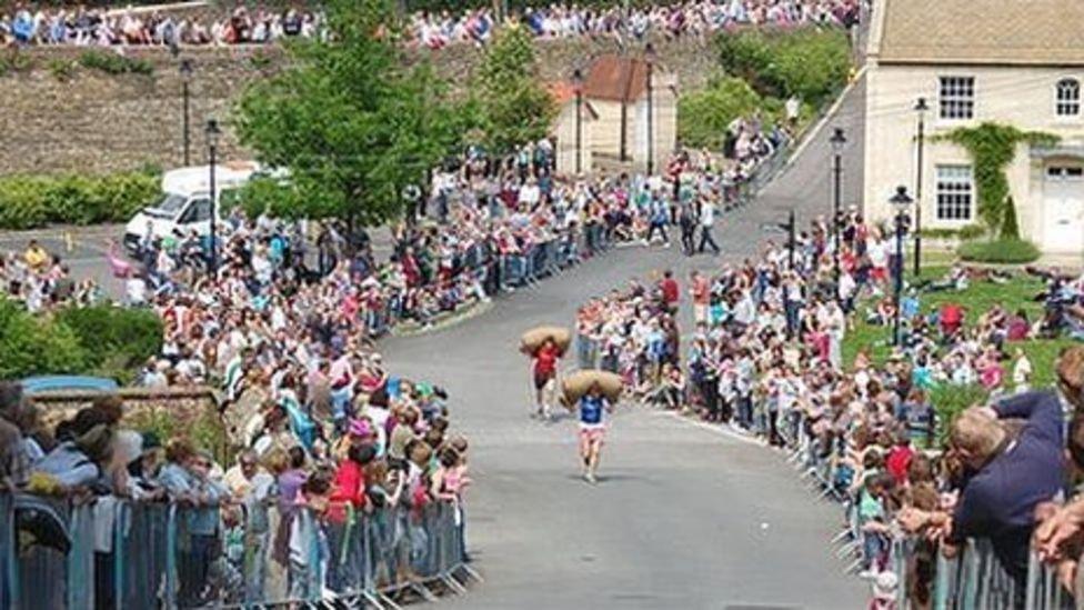 A man runs down Gumstool Hill in Tetbury with a sack on his back