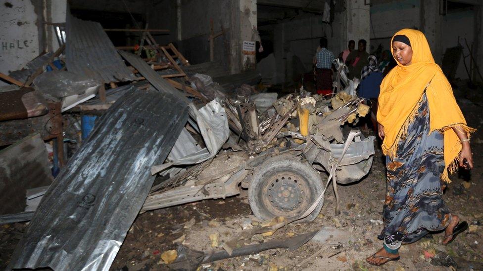 A Somali woman walks past the scene of a suicide car bomb attack near Juba hotel