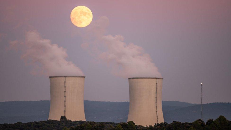 Moon above two cooling tower releasing plumes of vapour