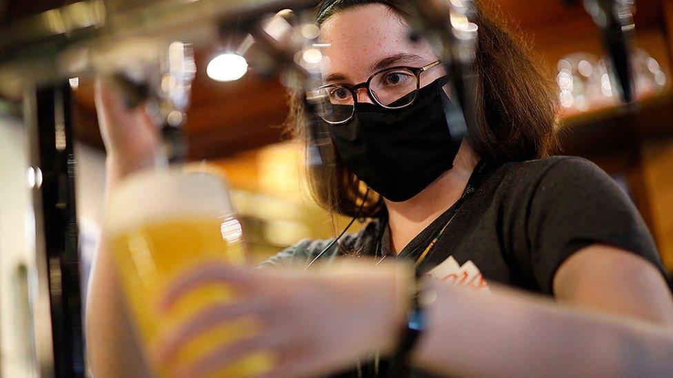 Woman pouring beer wearing a mask