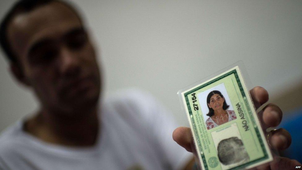 Marcello Felicio shows the ID card of his mother, Maria, who is among the 26 people missing