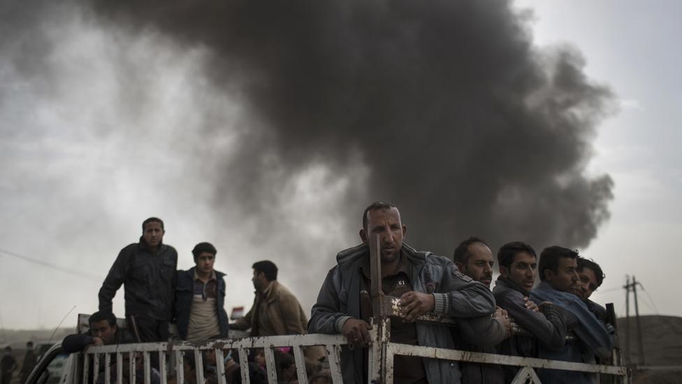 Displace people stand on the back of a truck at a checkpoint near Qayara, south of Mosul, Iraq, Tuesday, Nov. 1, 2016.