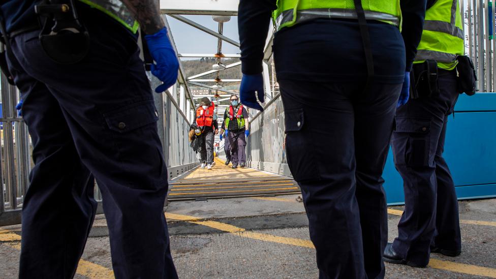 Asylum seekers arriving into Dover up the dock walkway ramp accompanied by Boarder Force officers after being on board a Boarder Force RIB boat, they were rescued in the English Channel while crossing in small inflatable dinghy on the 31st of March 2021 in Dover, Kent, United Kingdom.