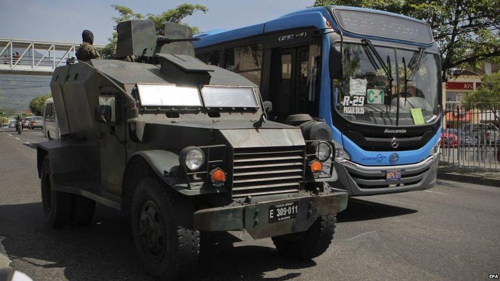 A vehicle of the Salvadorean Army patrols a street alongside a public bus in San Salvador on 29 July, 2015.