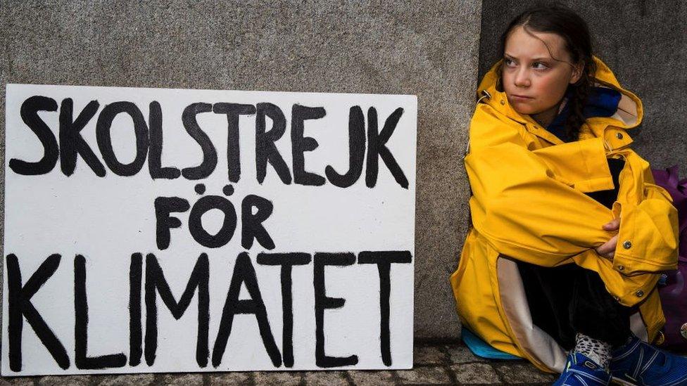 Greta in yellow mac with sign