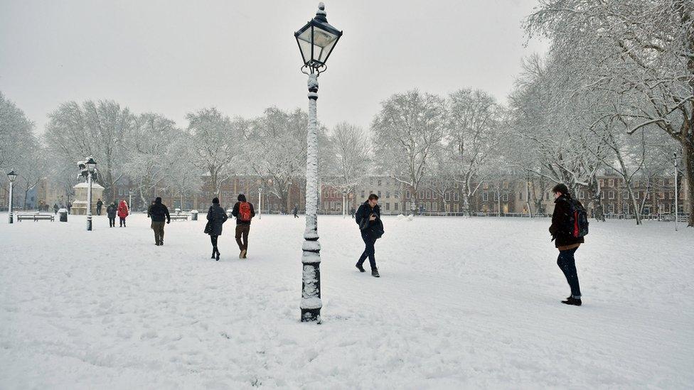 Pedestrians walk through Queen"s Square in Bristol after heavy snowfall