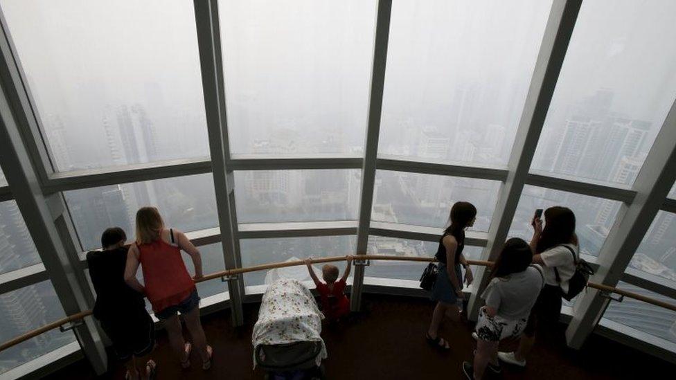 People look from an observation room at the haze-shrouded shopping district of Orchard Road in Singapore September 24, 2015.