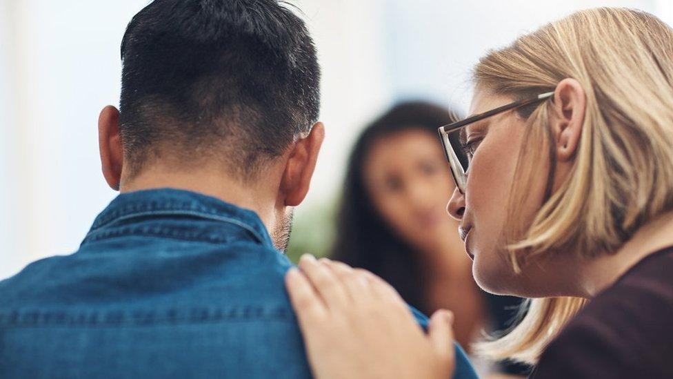 Woman with hand on young man's shoulder