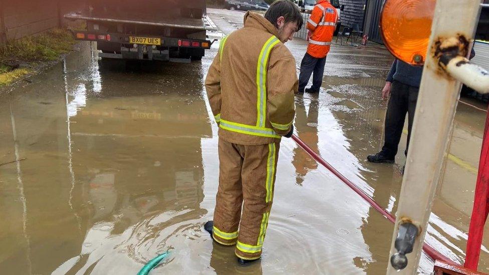 People pumping out water from a flooded shed