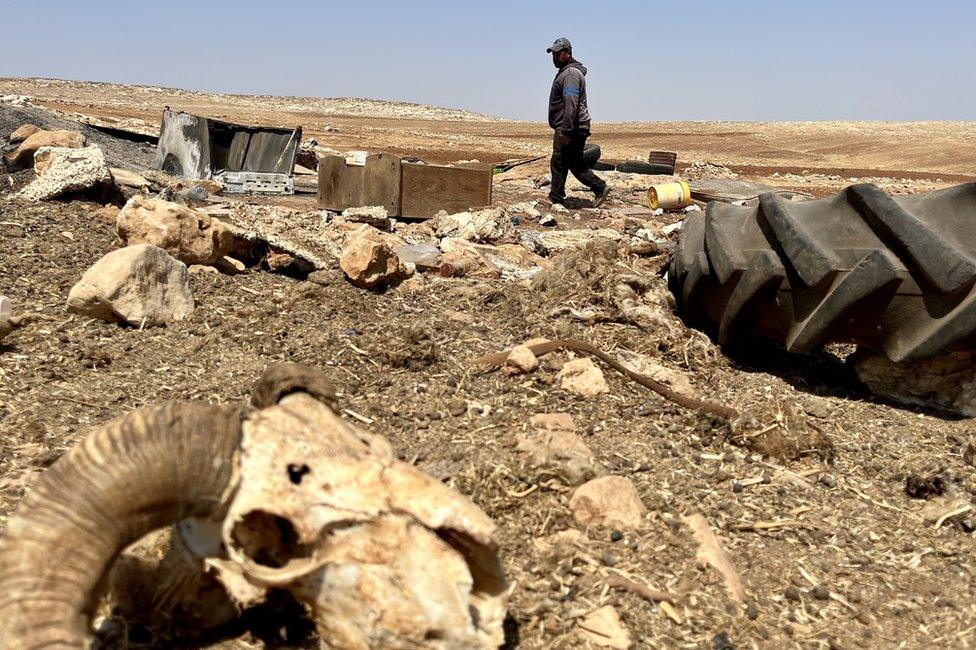 Ammar Abu Alia walks through the burnt remains of his home in al-Qabun