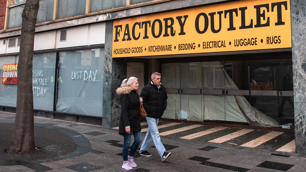 Couple walk past a vacant outlet in Slough on 13 December 2022