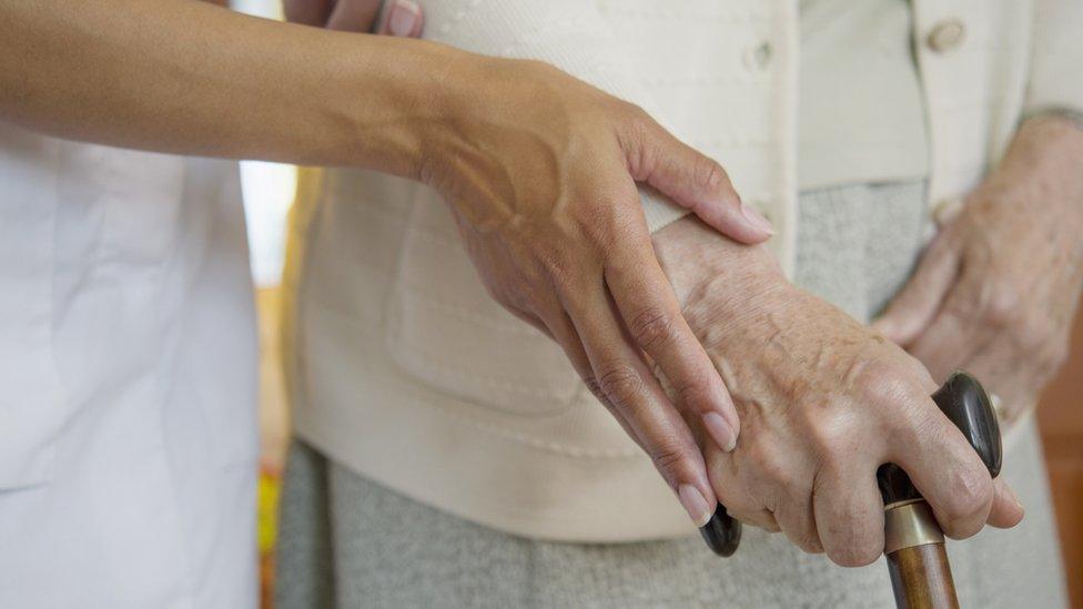 A carer guiding an elderly person