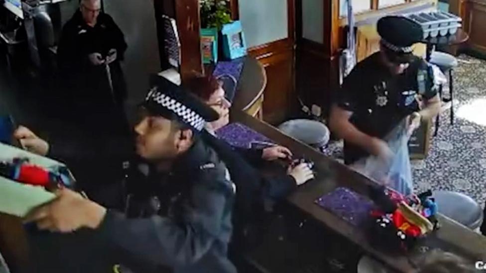 Officers putting golly dolls in a bag behind the bar