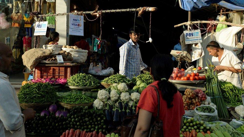 A sign advertising Indian mobile payments from Paytm hangs at vegetable stalls in Mumbai.