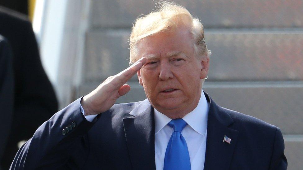 US President Donald Trump salutes the honour guard as he walks on the tarmac after disembarking Air Force One at Stansted Airport