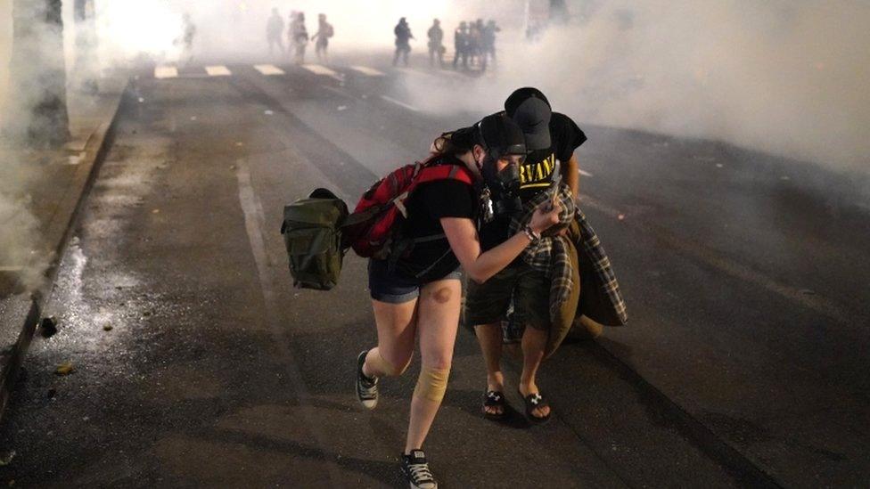 Two protesters flee through tear gas after federal officers dispersed a crowd of about a thousand at a courthouse in Portland, 21 July 2020