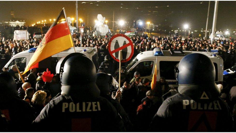 People attending an anti-immigration demonstration organised by rightwing movement Patriotic Europeans Against the Islamisation of the West (PEGIDA) walk past opponents of PEGIDA behind police cars, in Dresden, Germany October 19, 2015