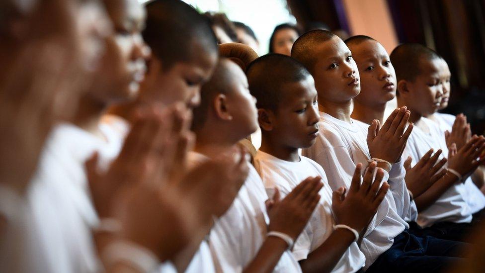 Members of the "Wild Boars" football team pray with holy string around their wrists during a ceremony to mark the end of the players' retreat as novice Buddhist monks at the Wat Phra That Doi Tung temple in the Mae Sai district of Chiang Rai province