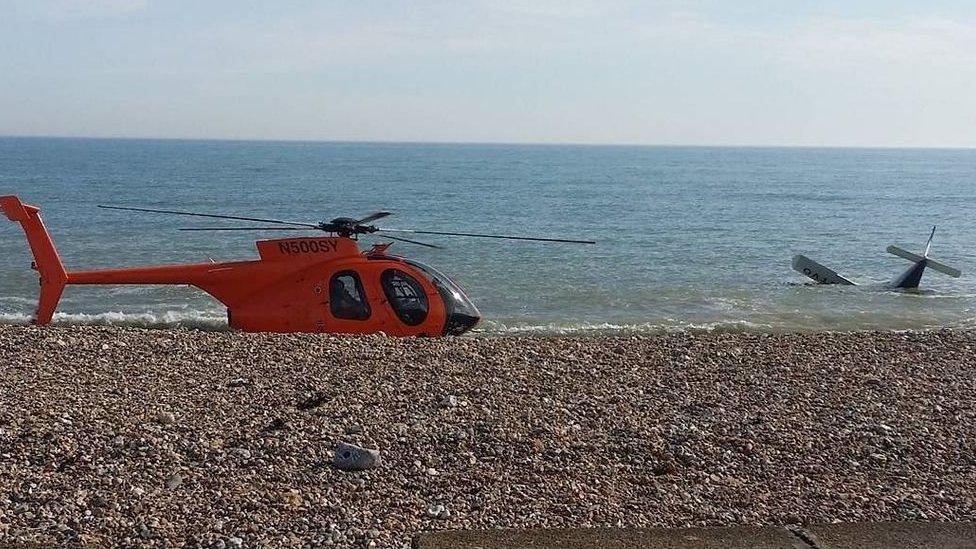 A photo shows the crashed plane and a rescue helicopter
