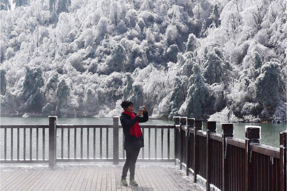 A woman takes a picture of the snow and ice in Hangzhou in eastern China's Zhejiang province on 25 January 2016.