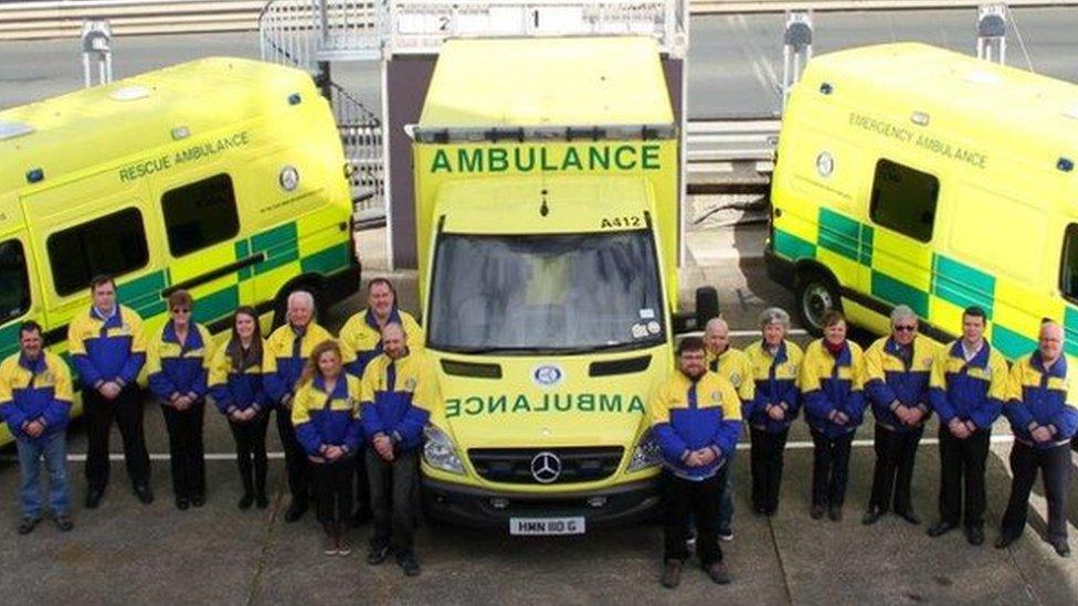 Volunteers standing in front of three ambulances