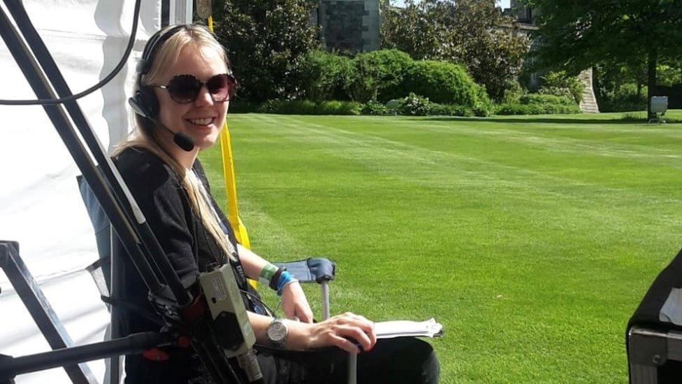 Liz producing television coverage on location, carrying paperwork with a headset on