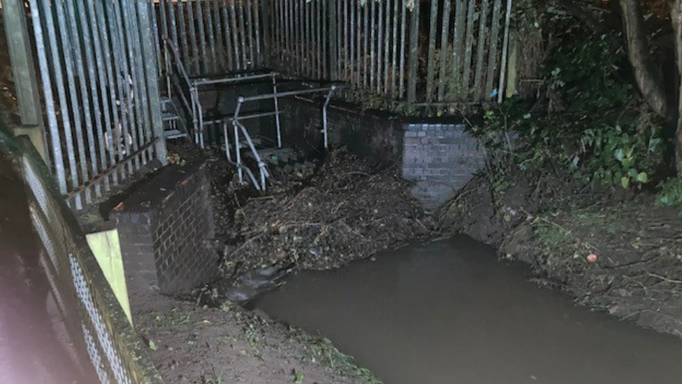 Debris on metal grill in waterway