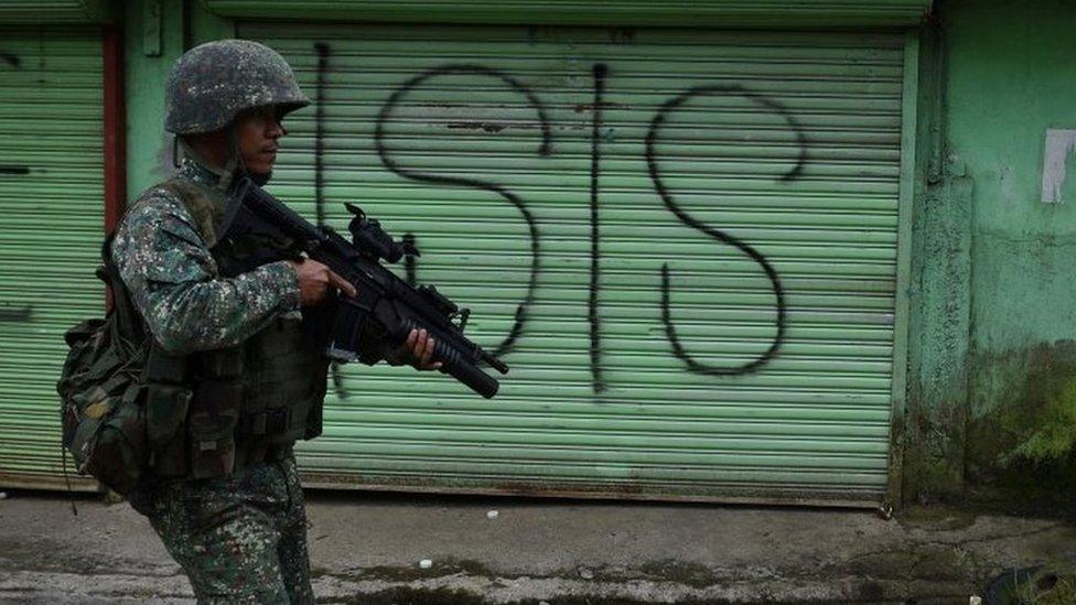 A Philippine Marine walks past graffiti during a patrol along a deserted street at the frontline in Marawi, on the southern island of Mindanao on 22 July 2017.