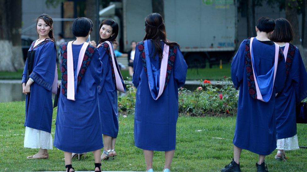 A group of students pose for photographs at a university in Beijing on June 8, 2015