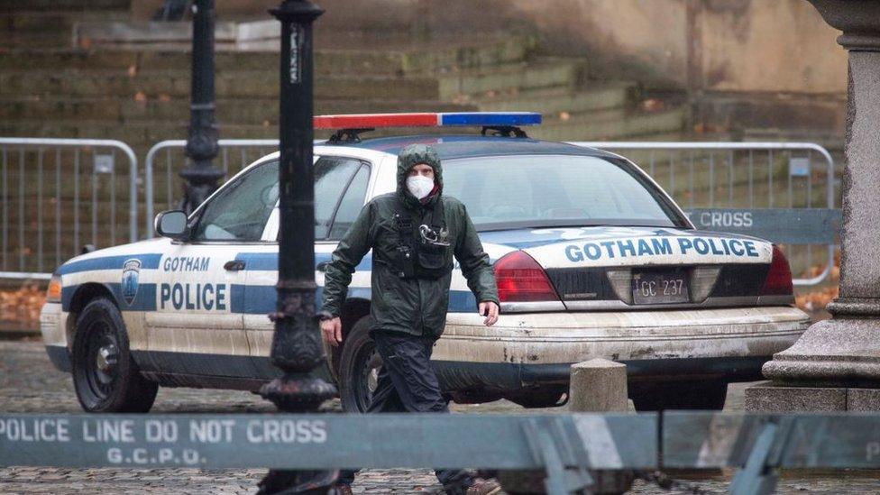 A production team member seen in front of a Gotham Police car in Liverpool