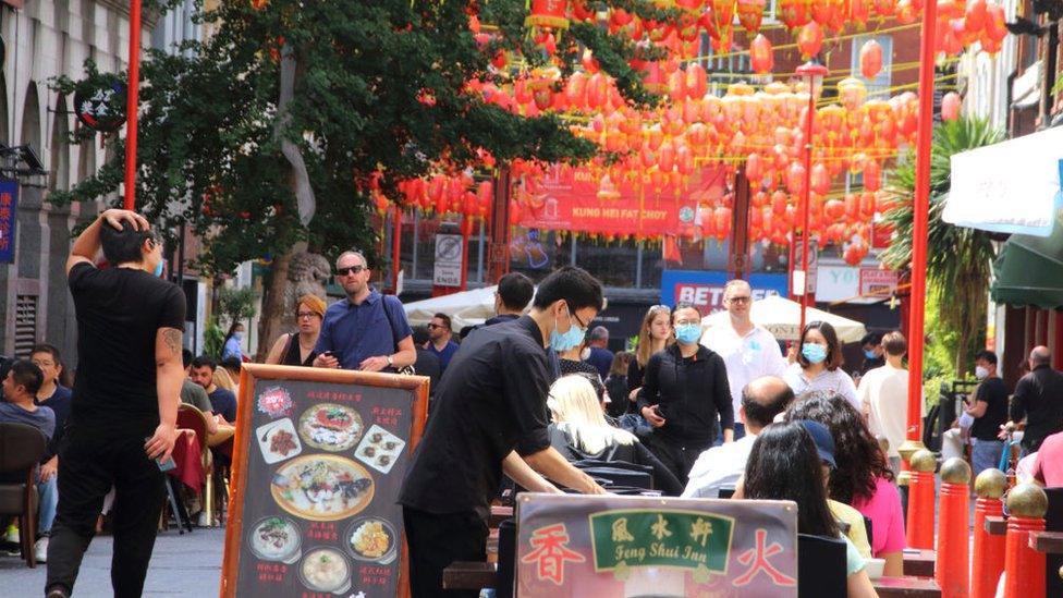 A waiter serves customers outside a restaurant in London's Chinatown during the Eat Out to Help Out scheme