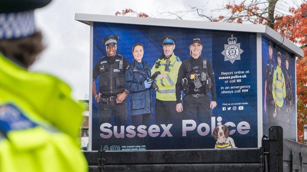 A Sussex Police pod on the back of a truck with a blurred police officer in the foreground