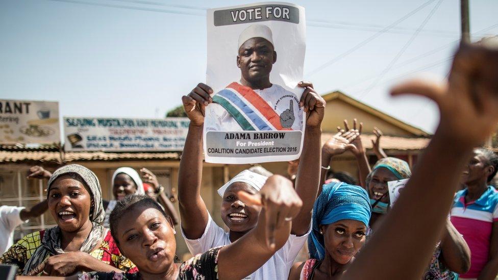 Supporters of Adama Barrow raise his election poster